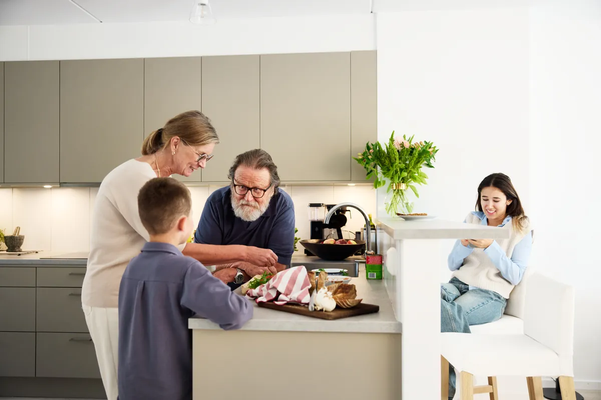 Tre generationer samlade kring ett kök i nordiskt dagsljus